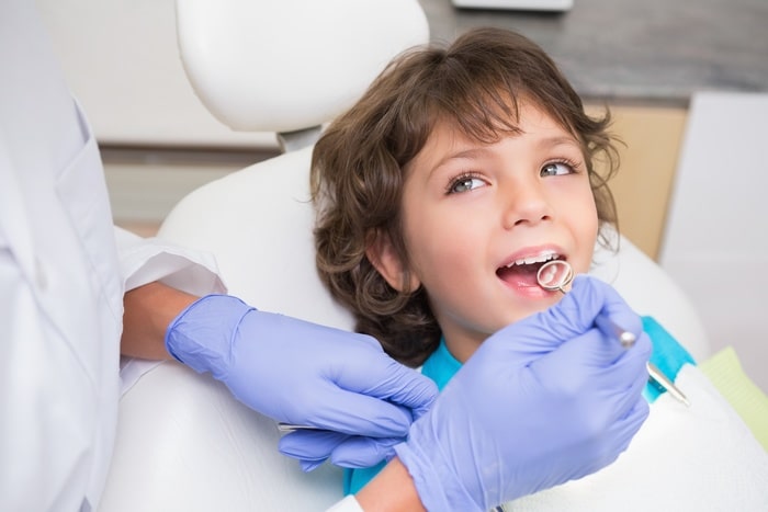 Pediatric dentist examining a little boys teeth Pediatric dentistry