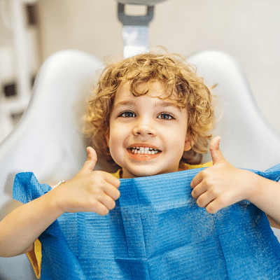 Childs first dentist visit 2 A child in a dental chair giving thumbs up, representing childs first dentist visit
